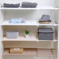 Adjustable wall-mounted closet storage rack filled with various items such as clothes, shoes, and a potted plant.